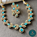 Necklace and earrings set with turquoise stones and gold accents on a gray surface, branded 'Naya Collections'.