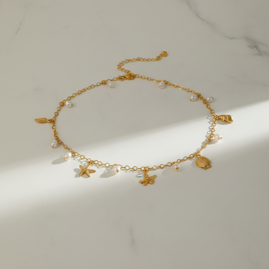 Gold charm necklace flat lay on white marble