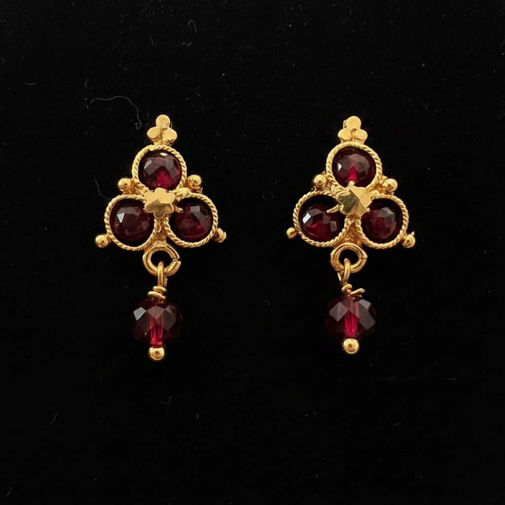 Gold garnet cross cluster drop earrings on black background