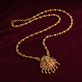 Antique gold Lakshmi necklace flat lay on burgundy velvet
